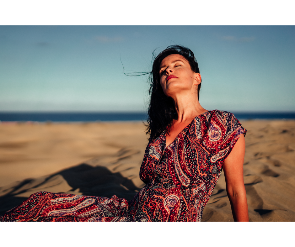 As vantagens dos vestidos de praia | Mulher de vestido sentada na areia da praia | Cia Marítima